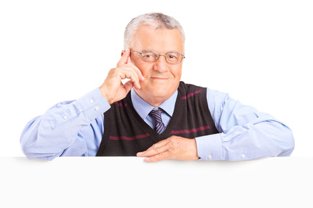 Smiling senior man posing behind blank panel isolated on white backgroundの写真素材