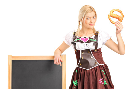 Young german girl in a traditional costume holding a pretzel isolated on white backgroundの写真素材