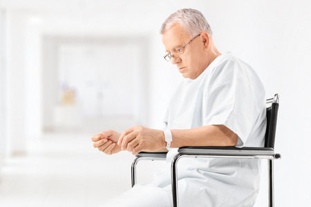 Worried mature patient sitting in a wheelchair in a hospital corridor の写真素材