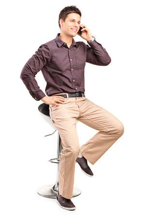 Young man in trendy clothes talking on the phone isolated on white backgroundの写真素材