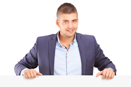 Young man standing behind a blank panel isolated on white backgroundの写真素材