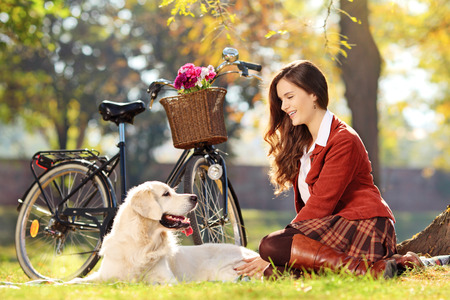 Pretty female sitting down with her dog in a parkの写真素材
