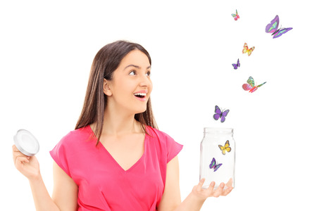 Happy girl watching butterflies escaping an open jar isolated on white backgroundの写真素材