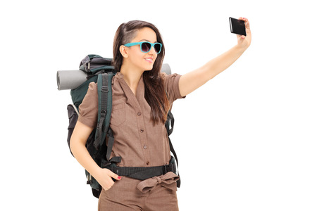 Female tourist taking selfie with cell phone isolated on white backgroundの写真素材