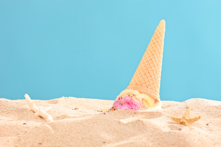 Studio shot of an ice cream splashed on sand on blue backgroundの写真素材