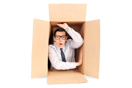 Young businessman trapped in a box isolated on white background