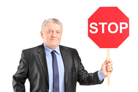 Mature businessman holding a stop sign isolated on white backgroundの写真素材