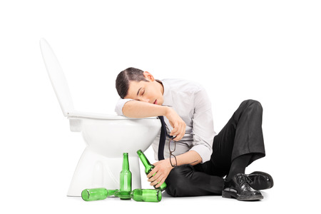 Male alcoholic sleeping on a toilet isolated on white backgroundの写真素材