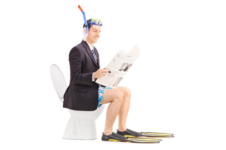 Man with snorkel reading the news on a toilet isolated on white backgroundの写真素材