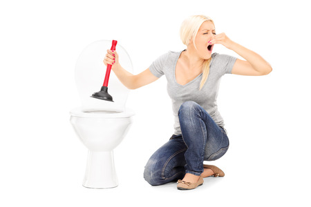 Woman unclogs a stinky toilet with plunger isolated on white backgroundの写真素材