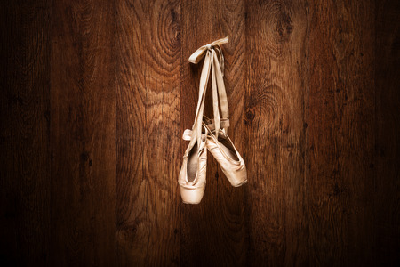 Ballet shoes hanged on a wooden wall with the focus on the shoesの写真素材