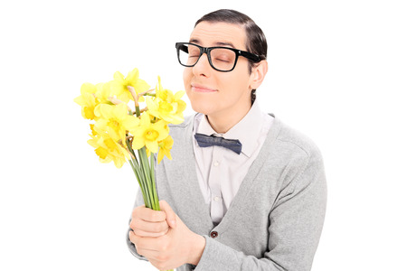 Young man smelling a bunch of yellow tulips isolated on white backgroundの写真素材