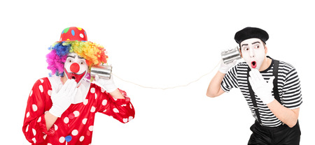 Clown and a mime artist talking through a tin can phone isolated on white background