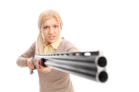 Angry girl pointing a rifle at the camera isolated on white backgroundの写真素材