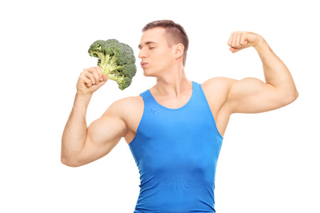 Muscular man kissing a huge piece of broccoli isolated on white backgroundの写真素材