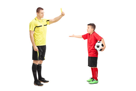 Football referee showing yellow card to a junior soccer player isolated on white background