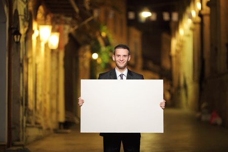 Businessman holding a blank panel in a city streetの写真素材