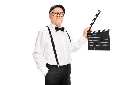 Studio shot of an artistic senior man holding a clapperboard and looking at the camera isolated on white backgroundの写真素材