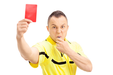 Furious football referee showing a red card and blowing a whistle isolated on white backgroundの写真素材