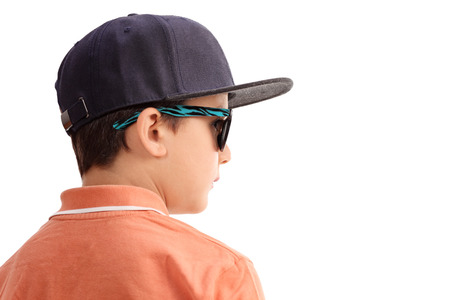 Cool little boy with a cap and sunglasses looking in the distance isolated on white backgroundの写真素材