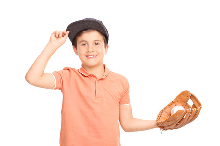 Cheerful little boy with a blue cap holding a baseball and looking at the camera isolated on white...