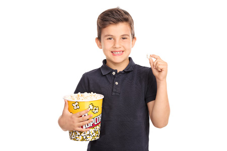 Joyful kid holding a big box of popcorn and looking at the camera isolated on white backgroundの写真素材