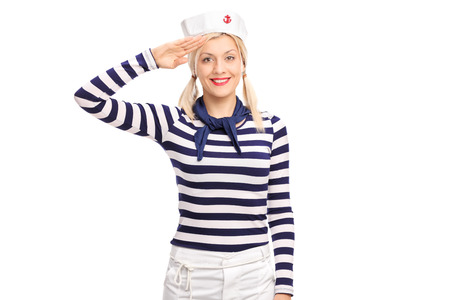 Young blond woman in a sailor outfit saluting towards the camera and smiling isolated on white backgroundの写真素材