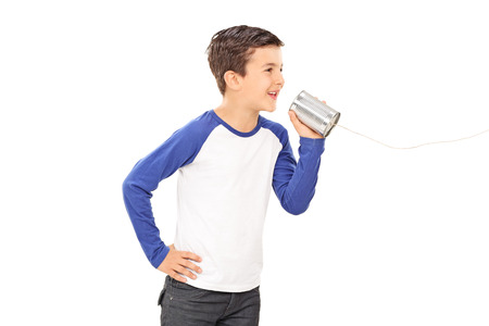 Studio shot of a cute little boy talking through a tin can phone isolated on white backgroundの写真素材