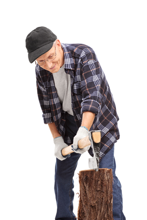Vertical shot of a senior in a blue checkered shirt splitting a log with an axe isolated on white backgroundの写真素材