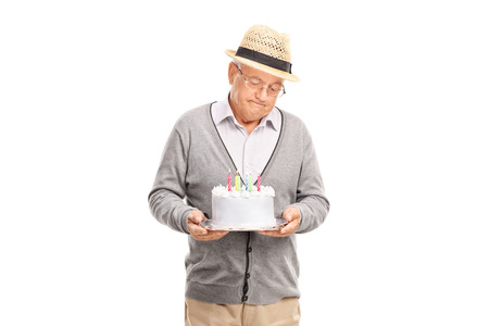 Studio shot of a lonely senior gentleman holding a birthday cake isolated on white background