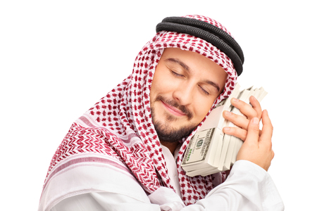Close-up on a young male Arab person sleeping on money and smiling isolated on white backgroundの写真素材