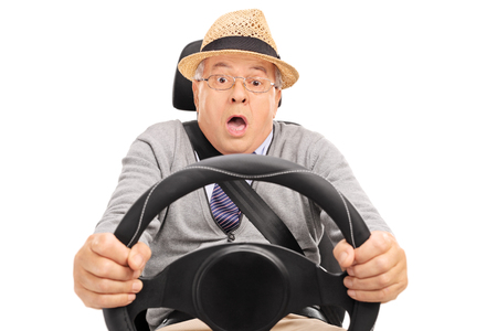 Scared senior holding a steering wheel and pressing the brake pedal to avoid a car crash isolated on...