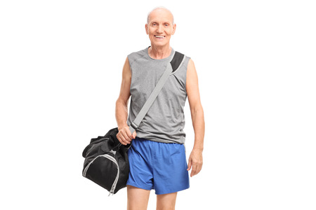 Active senior man in sportswear carrying a sports bag and walking isolated on white backgroundの写真素材