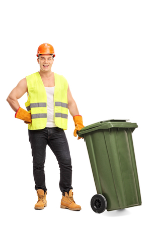 Full length portrait of a young male waste collector posing next to a green trash can isolated on white backgroundの写真素材