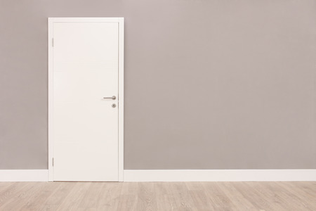 Shot of a closed white door on a gray wall in an empty room