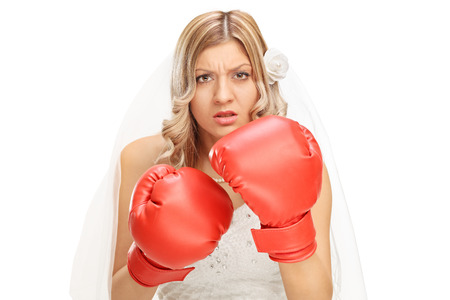 Studio shot of an angry young bride with red boxing gloves on her hands isolated on white backgroundの写真素材