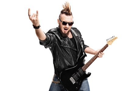 Studio shot of a punk rock guitarist playing guitar and making rock gesture isolated on white...
