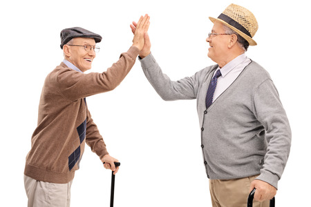 Two joyful senior gentlemen high-five each other isolated on white backgroundの写真素材