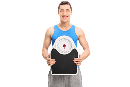 Studio shot of a young athlete holding a weight scale isolated on white backgroundの写真素材