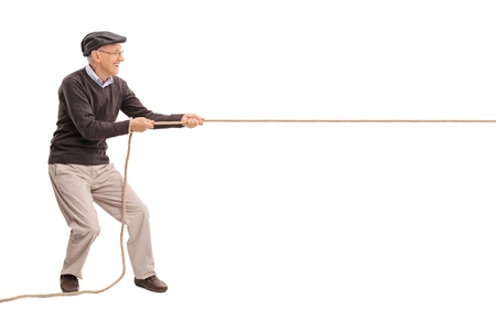 Full length profile shot of a senior gentleman pulling a rope isolated on white backgroundの写真素材