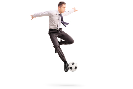 Studio shot of young businessman playing football shot in mid-air isolated on white backgroundの写真素材