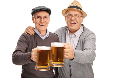 Two senior gentlemen making a toast with beer and looking at the camera isolated on white backgroundの写真素材