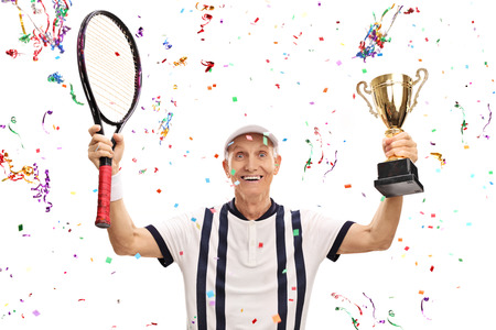 Joyful senior tennis player holding a trophy and celebrating victory isolated on white backgroundの写真素材