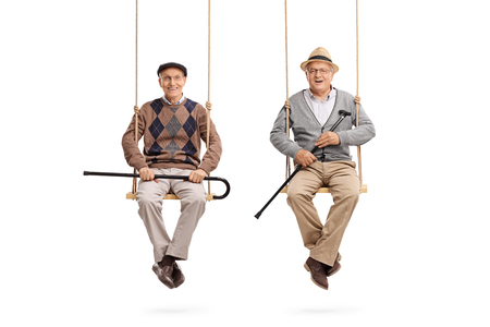 Two old friends sitting on wooden swings and looking at the camera isolated on white backgroundの写真素材