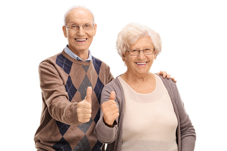 Senior man and woman giving thumbs up and looking at the camera isolated on white backgroundの写真素材