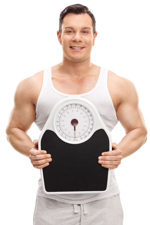 Vertical shot of a muscular young man holding a weight scale isolated on white backgroundの写真素材