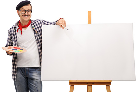 Eccentric artist posing next to a blank canvas on a wooden easel isolated on white backgroundの写真素材