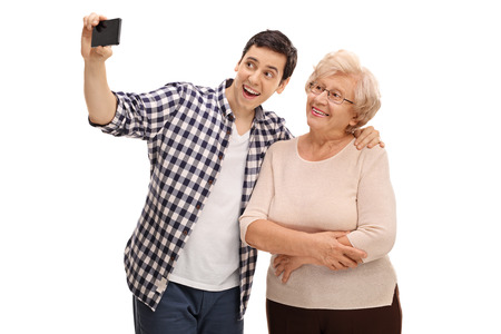 Young man and his grandmother taking selfie with cell phone isolated on white backgroundの写真素材