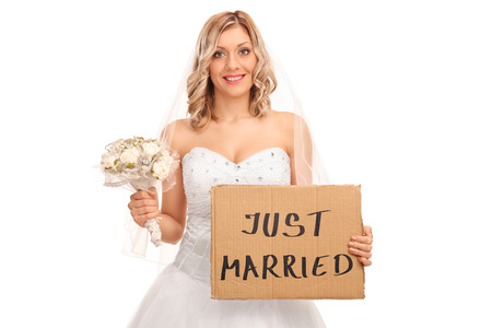 Joyful bride holding a wedding flower and a banner that says just married isolated on white backgroundの写真素材