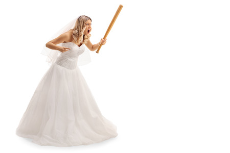 Full length portrait of an enraged bride threatening someone with baseball bat isolated on white backgroundの写真素材